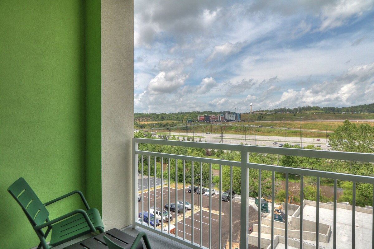 A balcony with a view of a parking lot and a distant building.