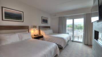 A hotel room with two beds, a TV, a window with curtains, and a view of the outside.