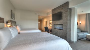 Habitación de hotel con dos camas, un televisor montado en una pared de piedra, un escritorio y una silla.