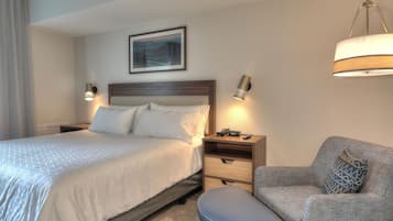 A hotel room with a bed, bedside tables, a chair, and a lamp.