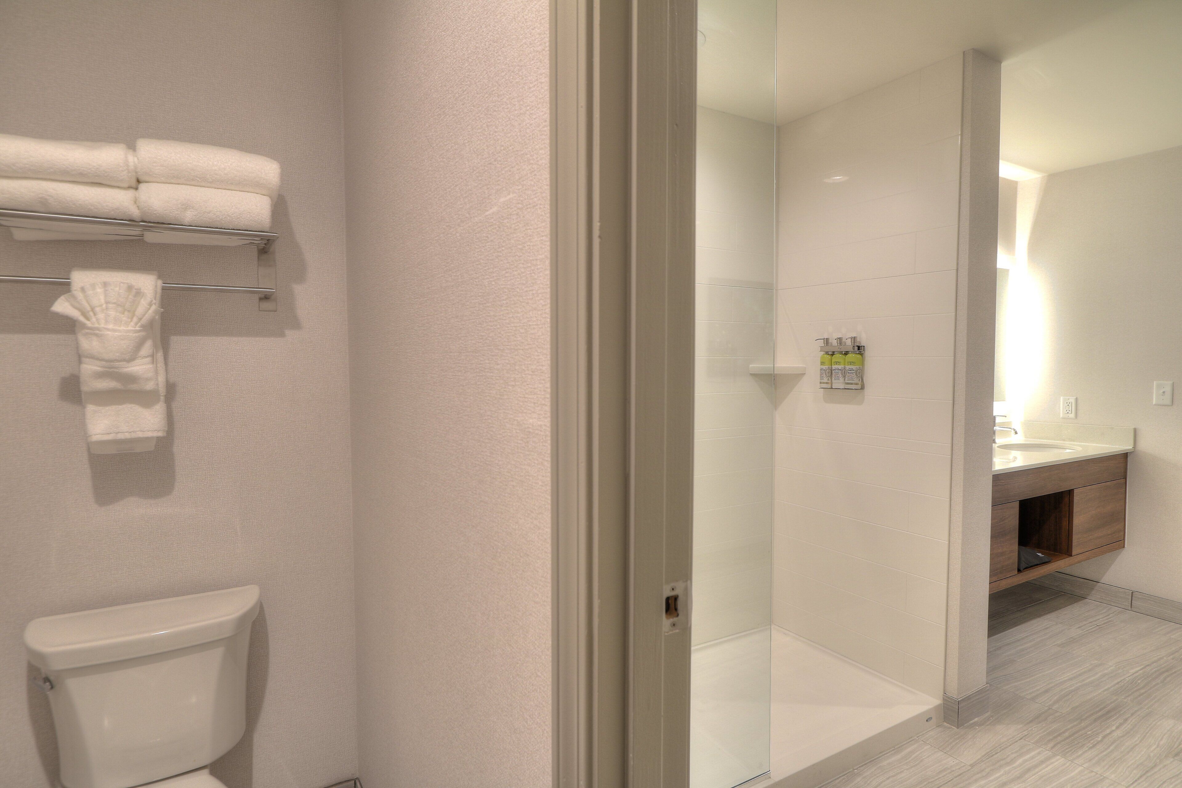 Een moderne badkamer met een toilet, een douche met glazen wanden en een wastafel met spiegel.