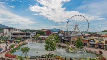 A public square with a large fountain, a Ferris wheel, and various shops and restaurants.