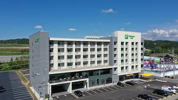 A multi-story hotel with a central atrium, a parking lot, and a view of the surrounding landscape.