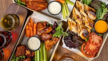 A variety of food items including wings, pretzels, and sandwiches, arranged on trays.
