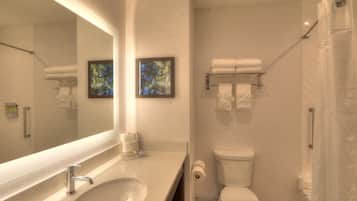 Un baño moderno con un espejo grande, un lavamanos, un inodoro y una zona de ducha.