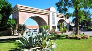 A brick building with arched entrances and a landscaped garden with agave plants. - Nova Park (Manavgat)