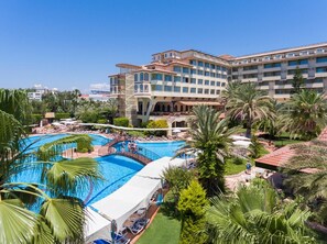 A hotel with a large swimming pool, palm trees, and a clear blue sky. - Nova Park (Manavgat)