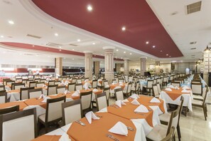 A large dining area with multiple tables set for guests, featuring a central column structure and a high ceiling. - Nova Park (Manavgat)
