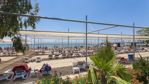 Zona de playa con numerosas tumbonas y sombrillas, una playa de arena y una vista despejada del mar.