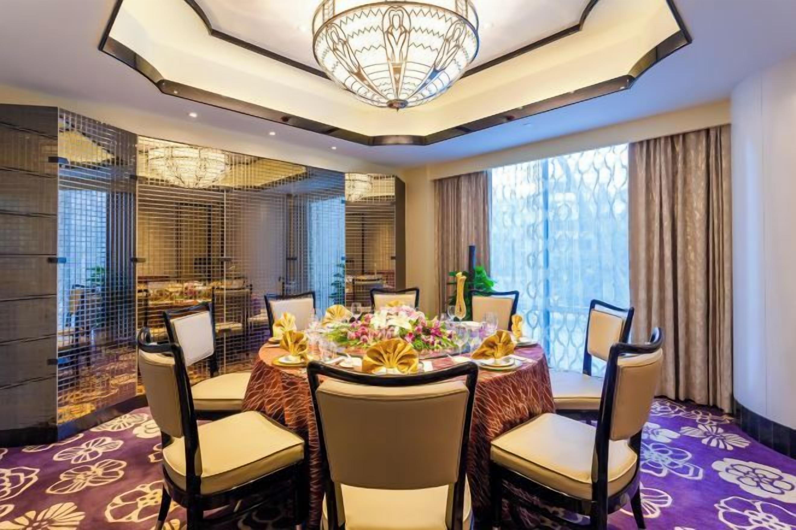 A dining area with a round table, chairs, and a chandelier.