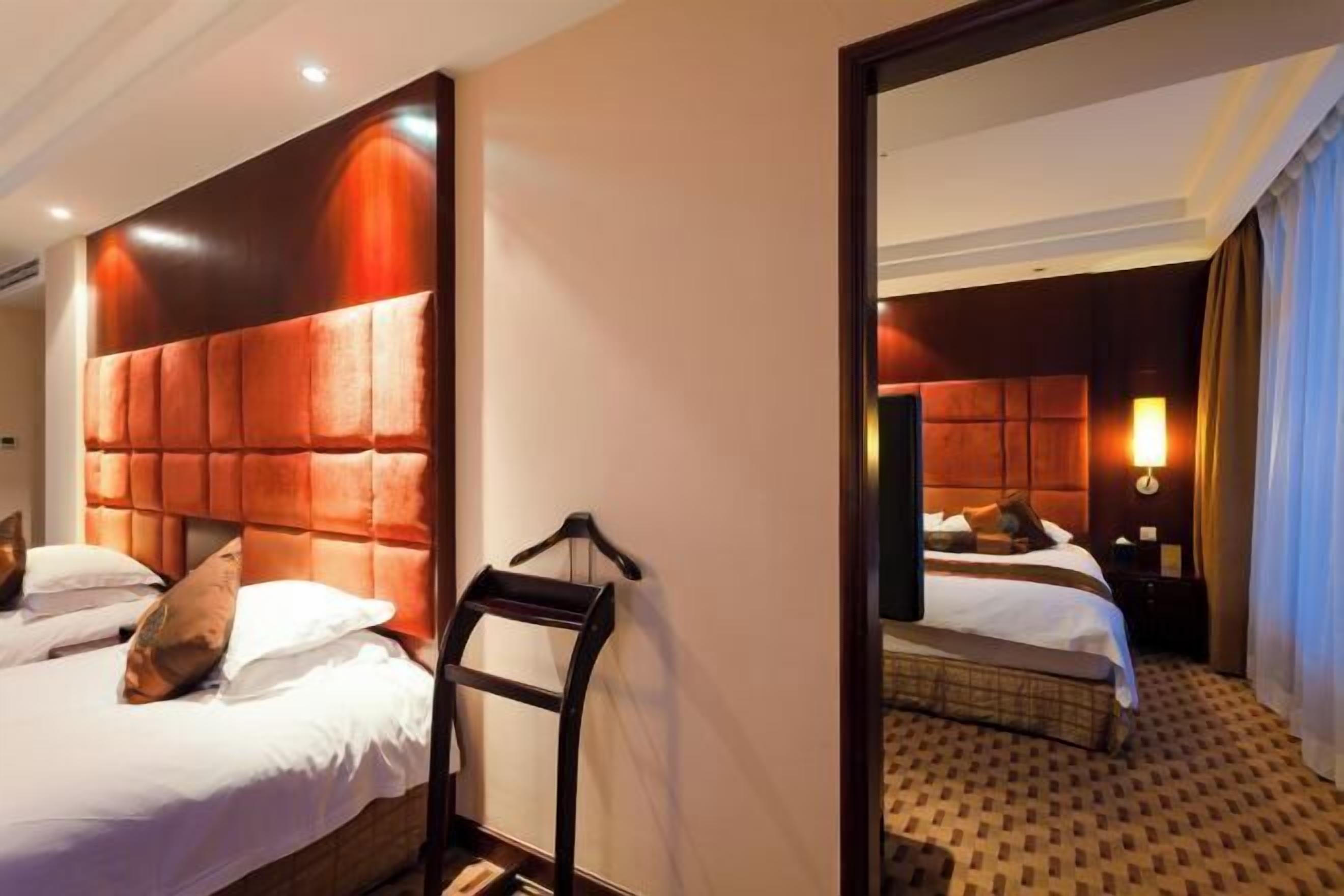 A hotel room with a large bed, a headboard, a bedside table, and a mirror.