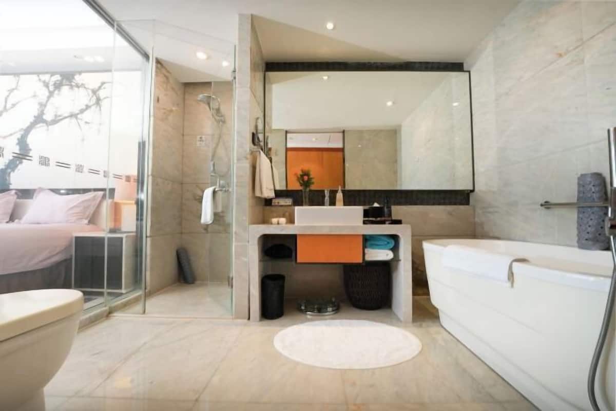 Un baño moderno con cabina de ducha de vidrio, una bañera blanca y un lavamanos con espejo.