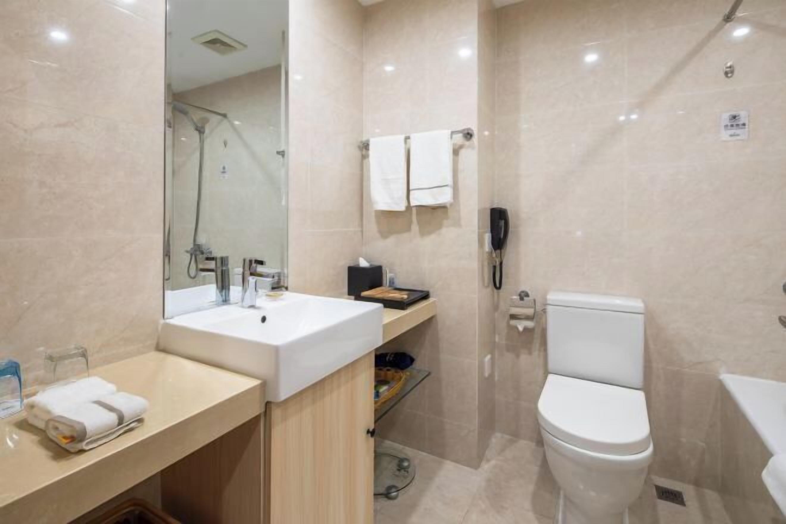 A modern bathroom with a large mirror, a sink, a toilet, and a shower area.