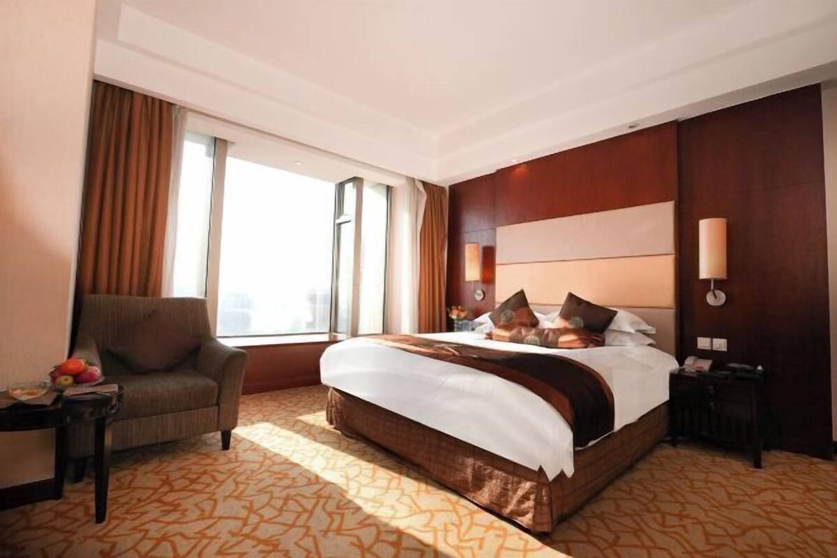 Habitación de hotel con una cama grande, una silla, una mesita de noche y una ventana con cortinas.