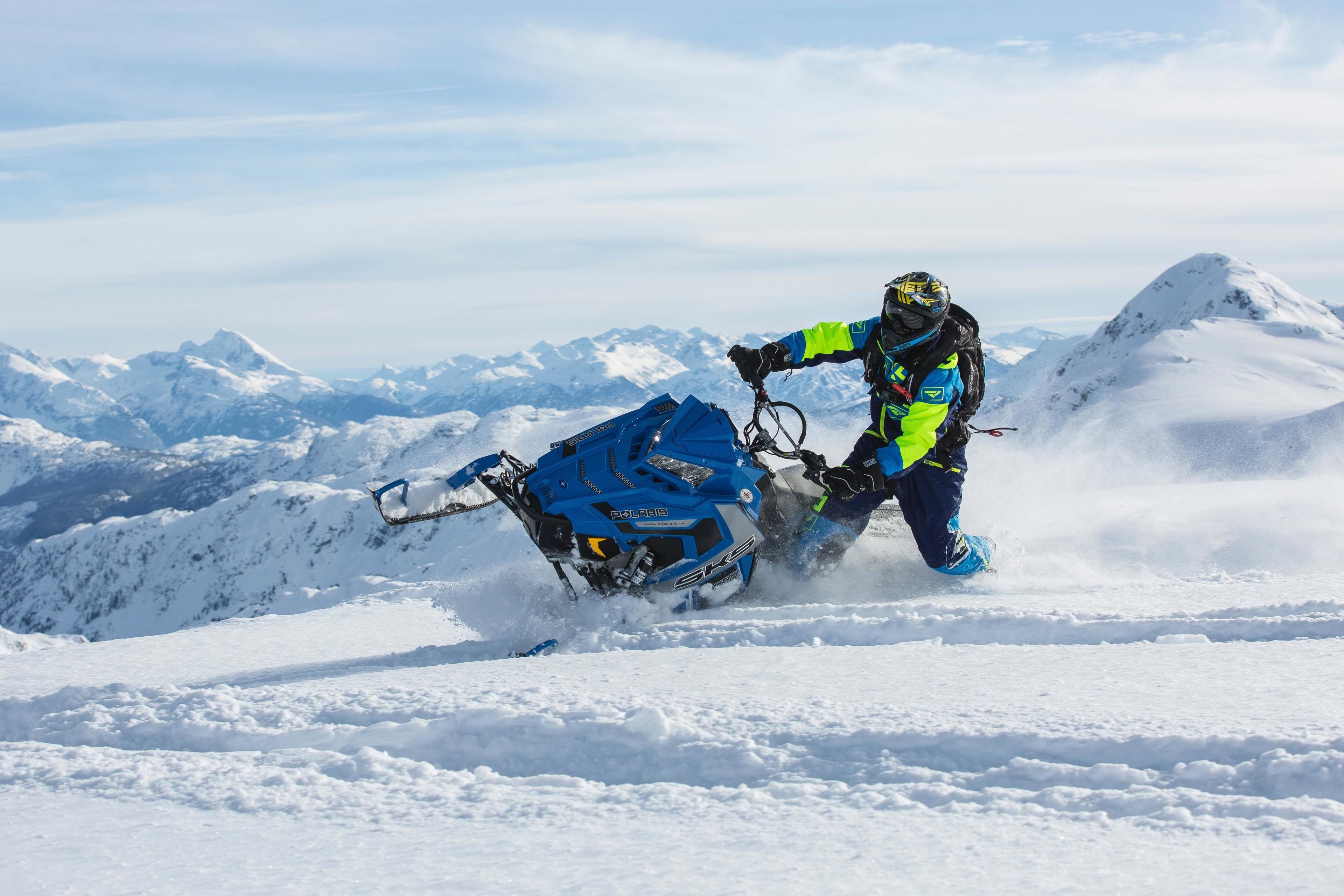 Una moto de nieve con un conductor en una montaña nevada.