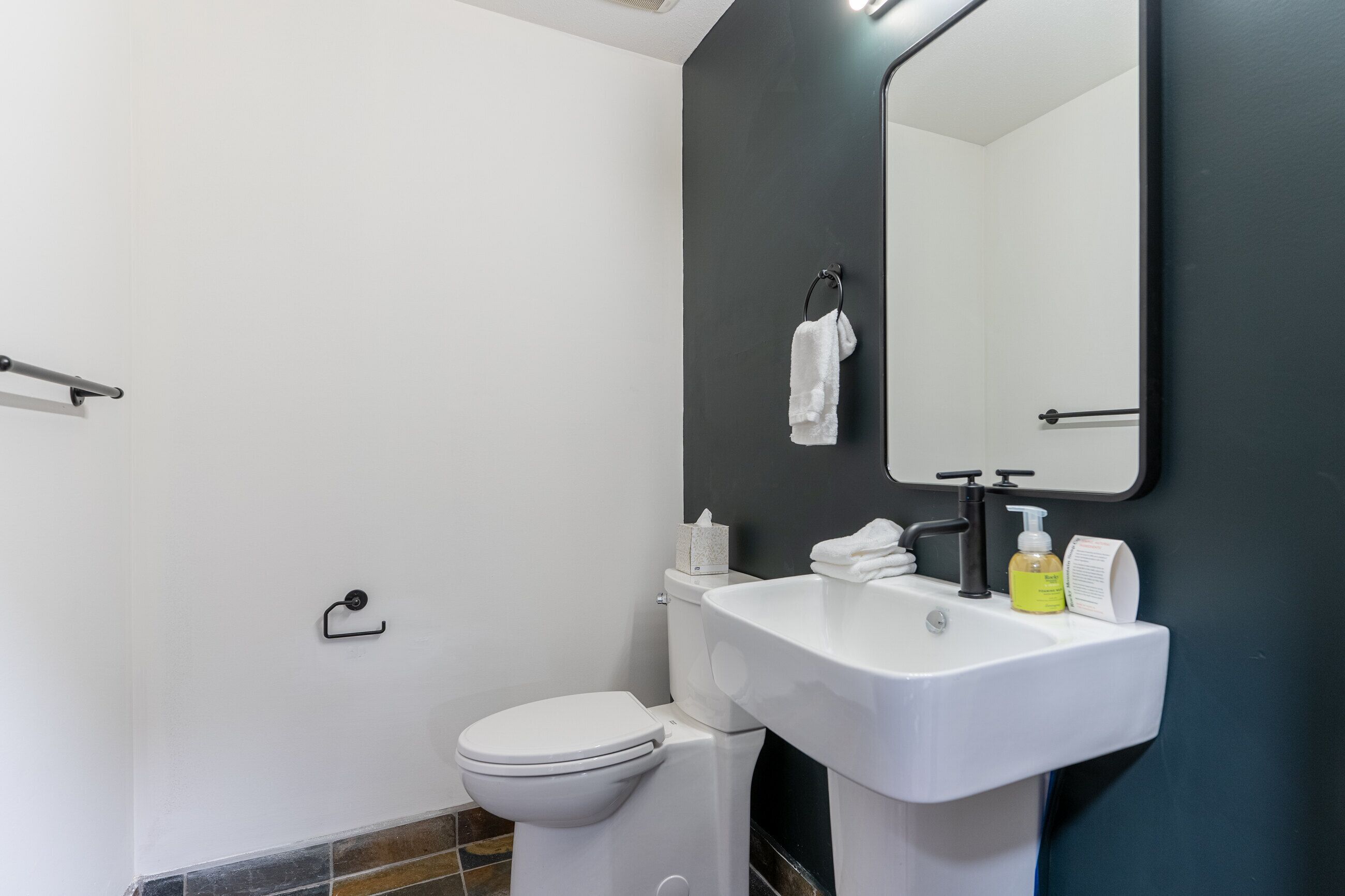 A modern bathroom with a white toilet, a white sink, and a mirror.
