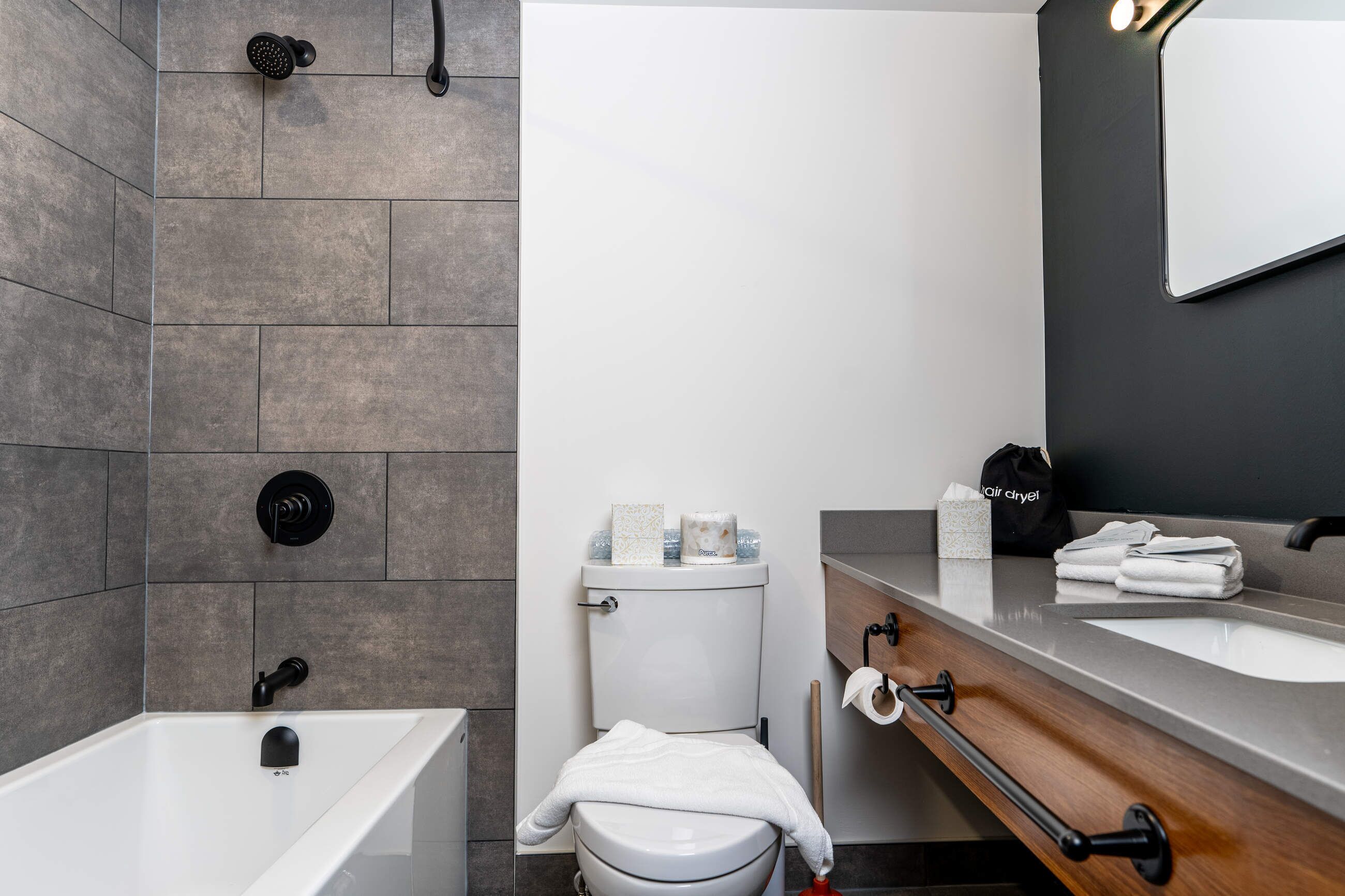 A modern bathroom with a bathtub, toilet, and vanity with a mirror.