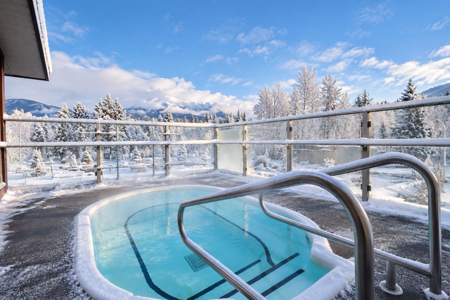 A pool area with a view of snow-covered trees and mountains.