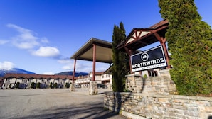 Entrada de un hotel con un letrero que dice "Northwinds Hotel by Basecamp", paredes de piedra y una zona de estacionamiento techada.