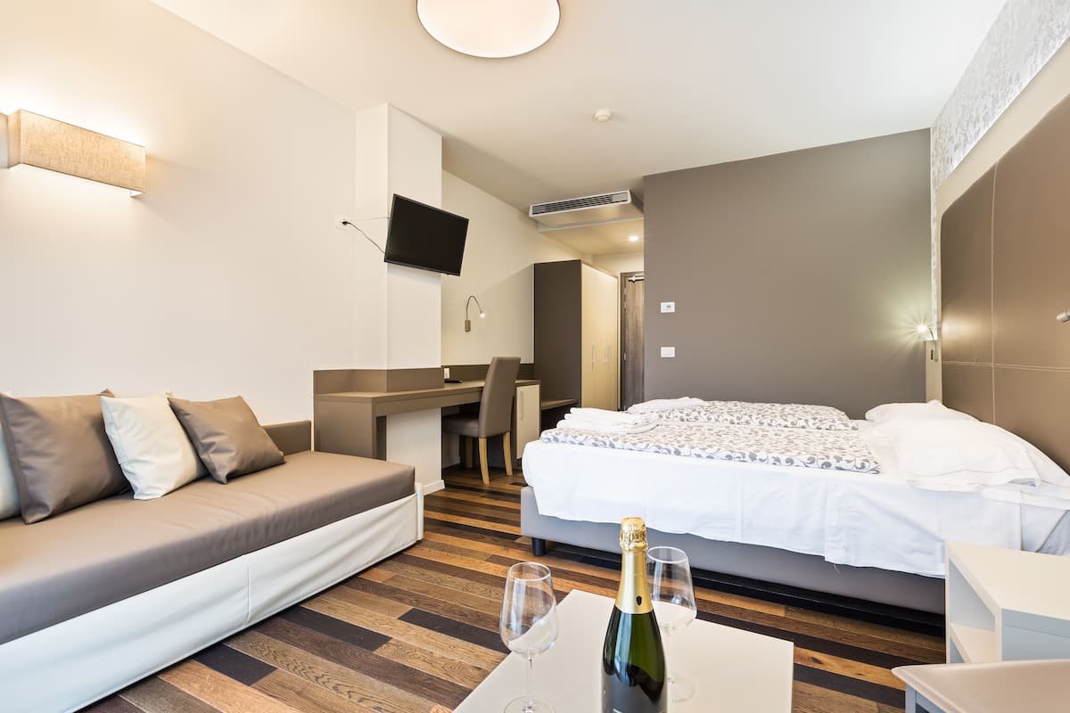 Una habitación de hotel moderna con cama, sofá, escritorio y televisor.