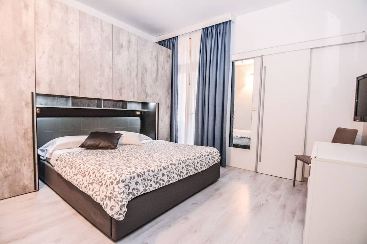 Un dormitorio moderno con una cama grande, un armario y un escritorio pequeño.