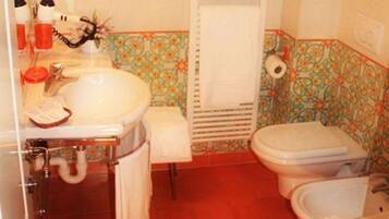 Un baño con lavamanos, inodoro, bidé y ducha.
