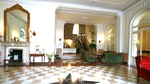 A lobby with a checkered floor, a star-shaped design, a fireplace, and a staircase leading to another level. - Hotel Excelsior Splendide (Bellagio)