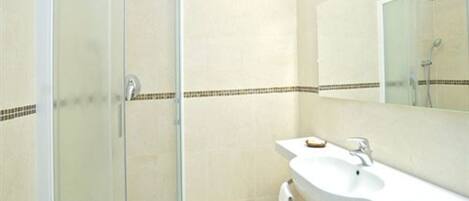 A bathroom with a glass-enclosed shower, a white sink, and a mirror.