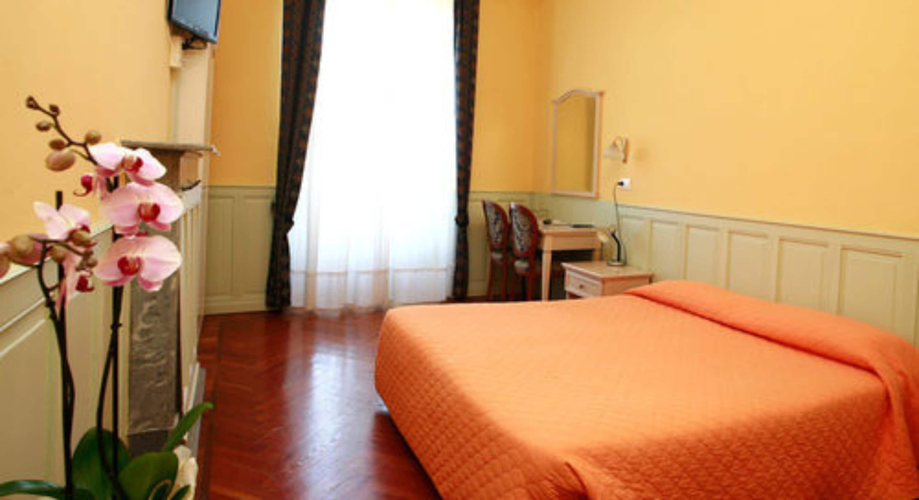 Une chambre d’hôtel avec un lit, un bureau, une chaise et un miroir.