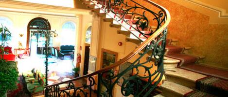 A grand staircase with ornate metal railings leading to a landing.