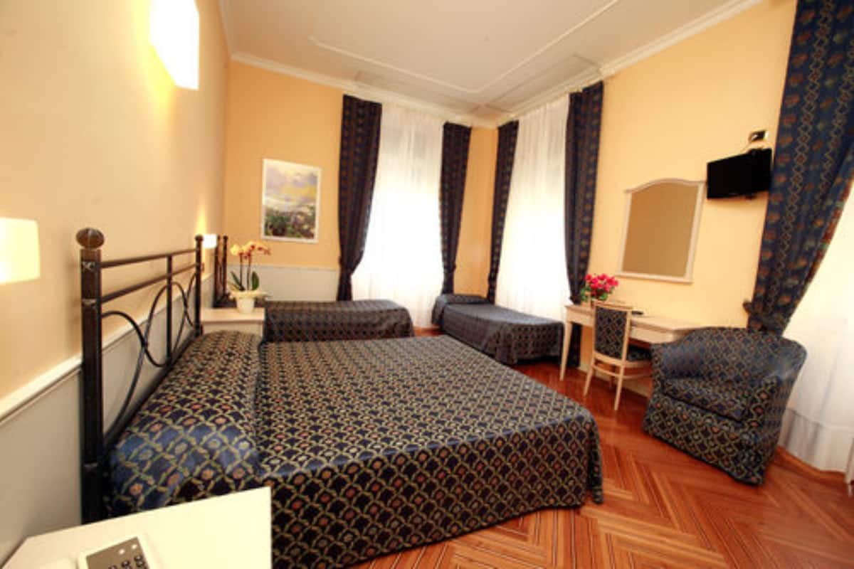 A hotel room with a bed, a chair, a desk, and a television.