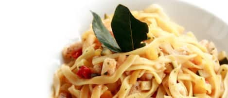 A plate of pasta with a bay leaf garnish.