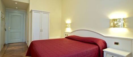 A bedroom with a bed, a nightstand, a wall-mounted lamp, and a wardrobe.