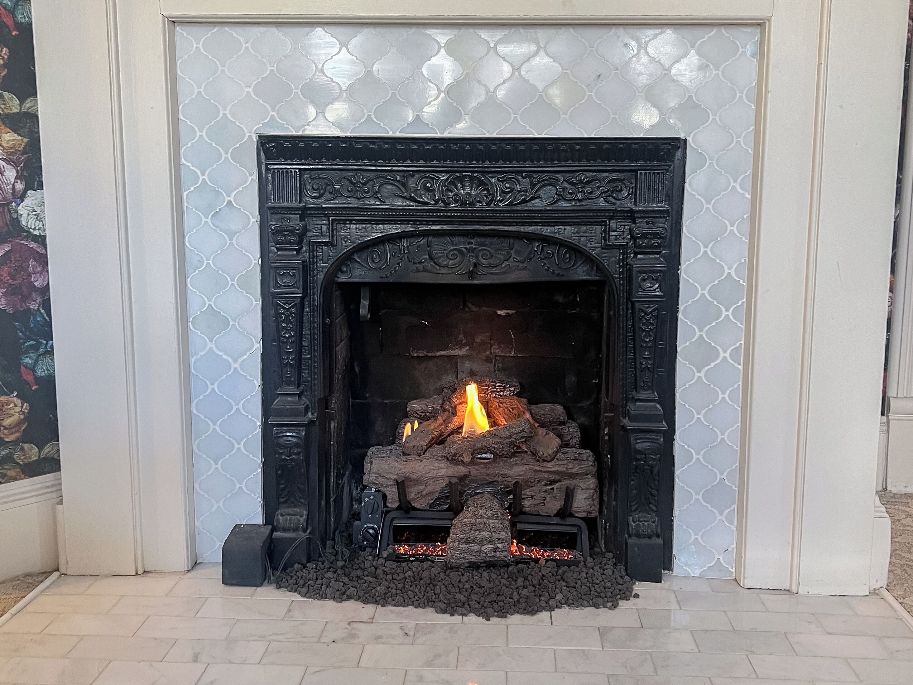 A fireplace with a fire burning inside, surrounded by decorative stone and wood.