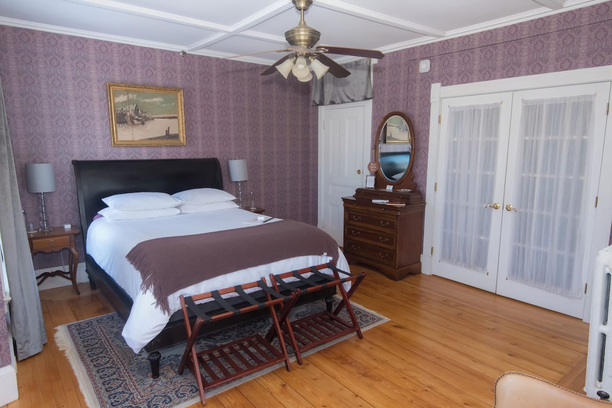 Un dormitorio con cama, cómoda, espejo y armario.