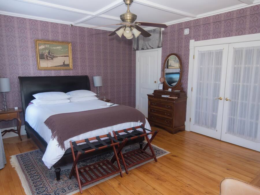 A bedroom with a bed, dresser, mirror, and wardrobe.