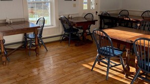 A dining area with a wooden table and chairs, a chandelier, and an exit sign. - The Kendall Inn (Freeport)