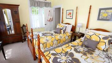 A bedroom with two beds, a wooden wardrobe, a mirror, and a window with curtains.