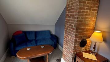 Une pièce chaleureuse avec un canapé bleu, une table basse en bois, un mur décoratif en briques et une lampe sur une table d’appoint.