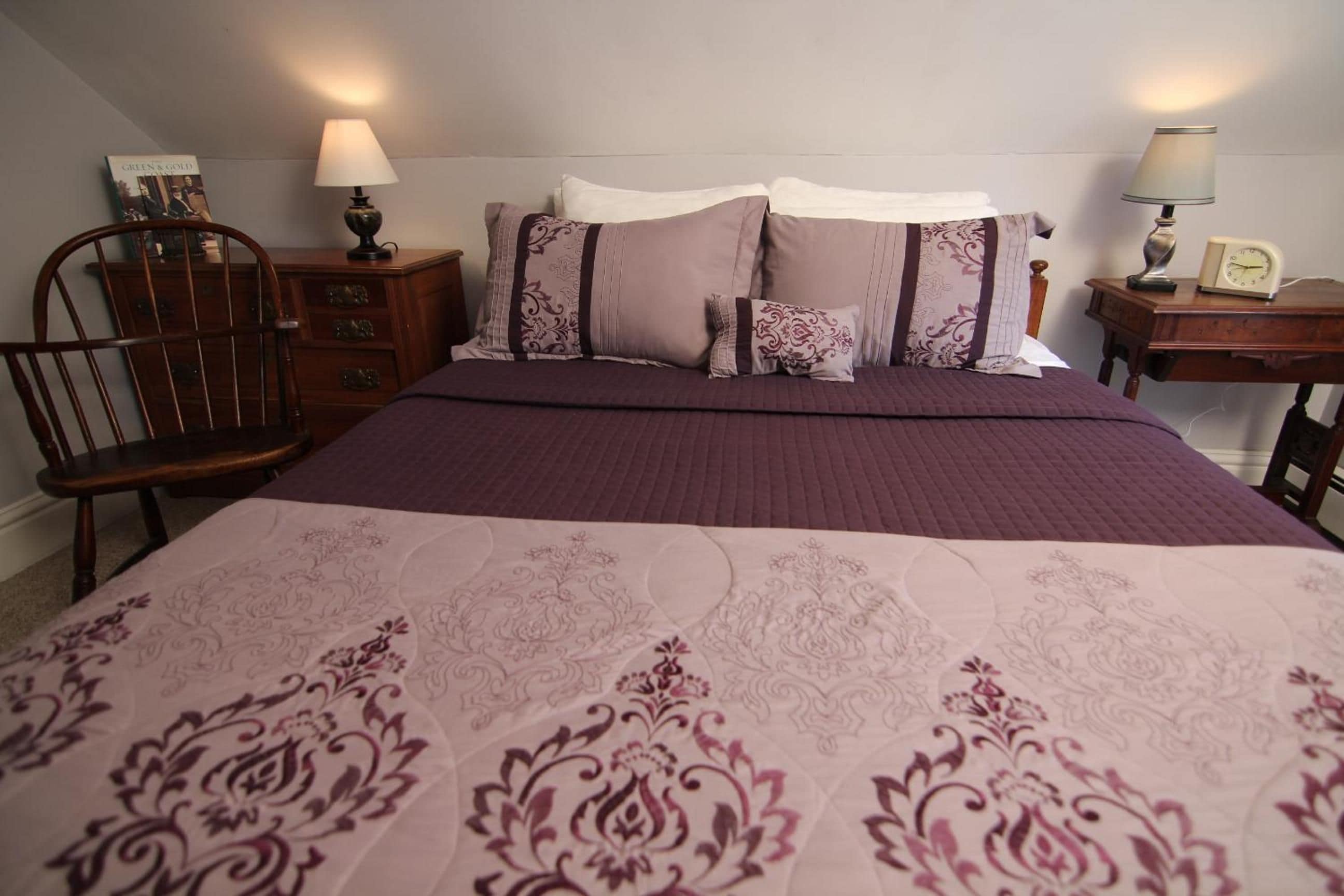 A bedroom with a bed, two nightstands, a chair, and a dresser.