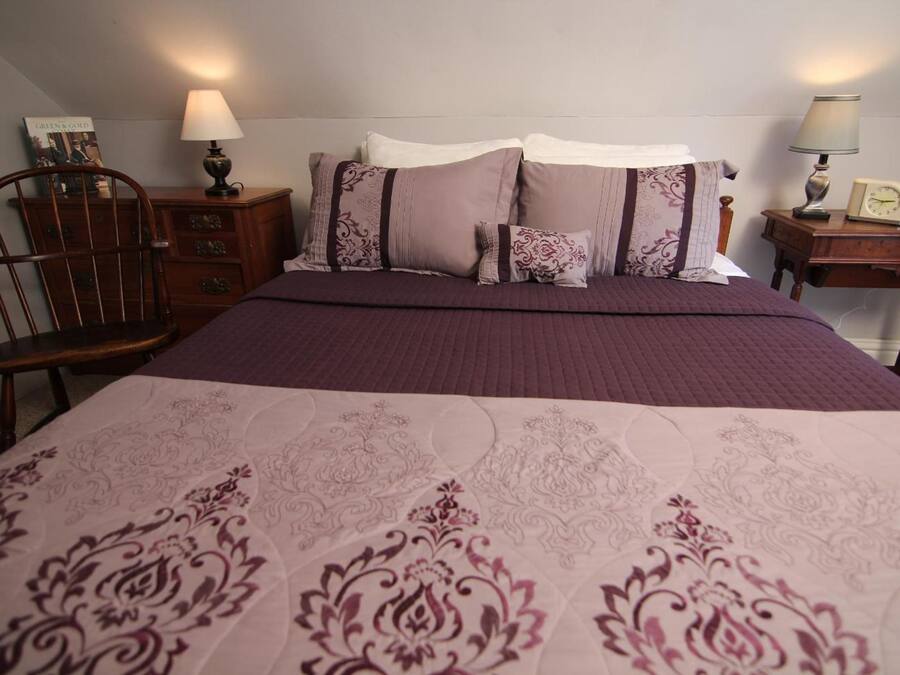 Een slaapkamer met een bed, twee nachtkastjes, een stoel en een kledingkast.