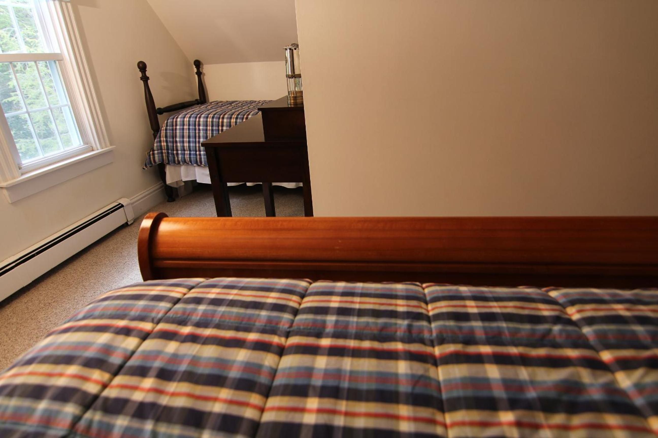 Une chambre à coucher avec un lit au premier plan et un lit plus petit à l’arrière-plan.