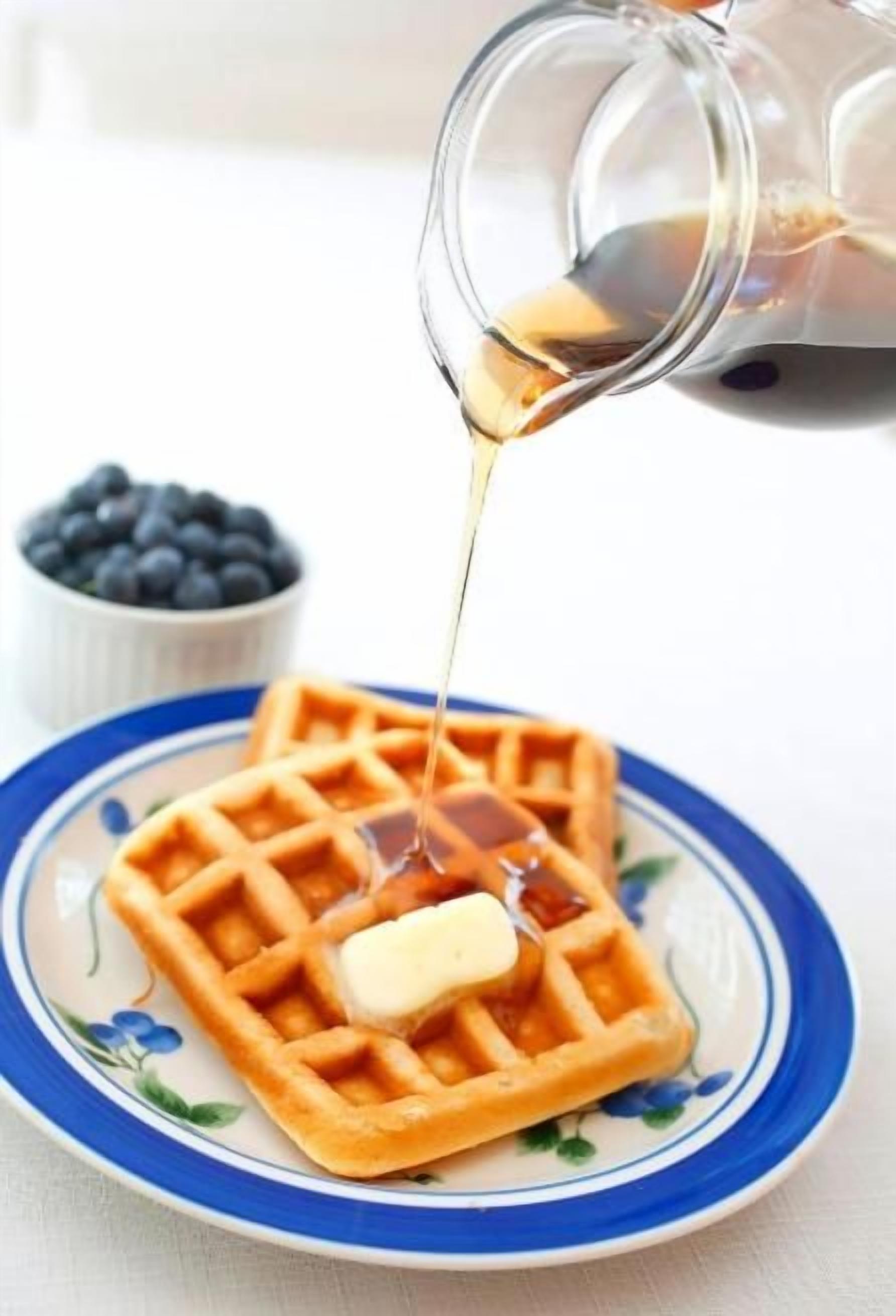 A waffle with syrup and butter on a plate.