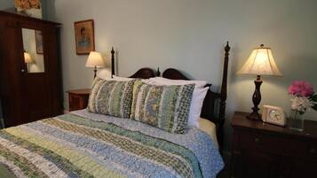 A bedroom with a four-poster bed, a bedside table with a lamp, a clock, and a mirror.