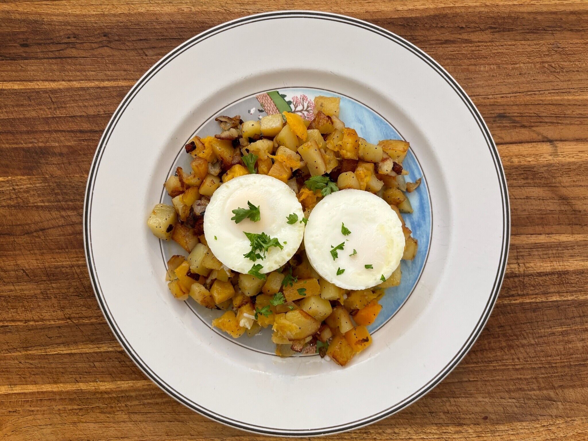 Un plato de comida con patatas y dos huevos pochados, decorado con perejil.