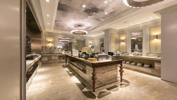 A spacious hotel lobby with a marble floor, a central bar area, and a modern ceiling design.