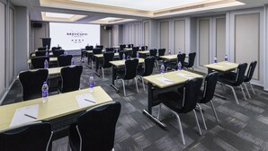 A conference room with rows of tables, chairs, and a projection screen displaying 'Mercure Hotels'. - Mercure Xi'an Downtown (Xi'an)
