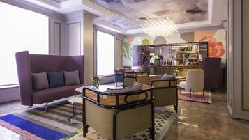 A modern lounge with a sofa, armchairs, a coffee table, a patterned rug, and a bookshelf.