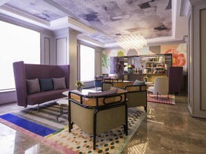 A modern lounge with a sofa, armchairs, a coffee table, a patterned rug, and a bookshelf. - Mercure Xi'an Downtown (Xi'an)