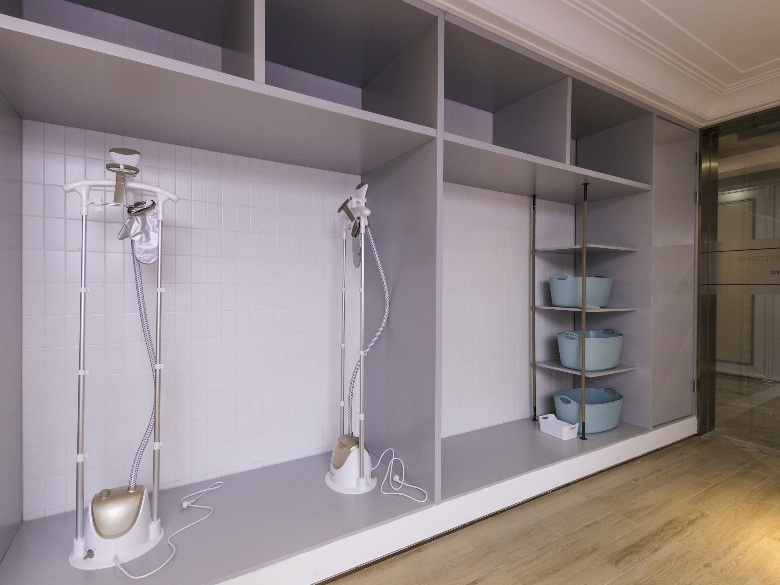 A bathroom with a shower, a towel rack, and storage shelves.